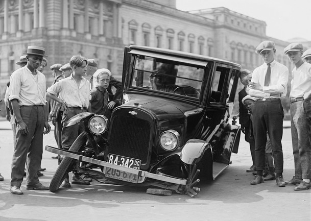 A classic car broken down on a street in 1930s America.